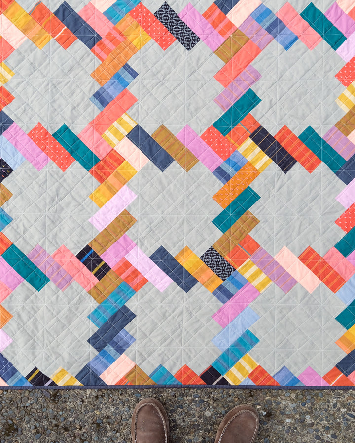 The Phoebe Quilt made with vibrant fabrics, showcasing a versatile pattern that works with jelly rolls, fat eighths, fat quarters, and scraps in a variety of fabric collections.