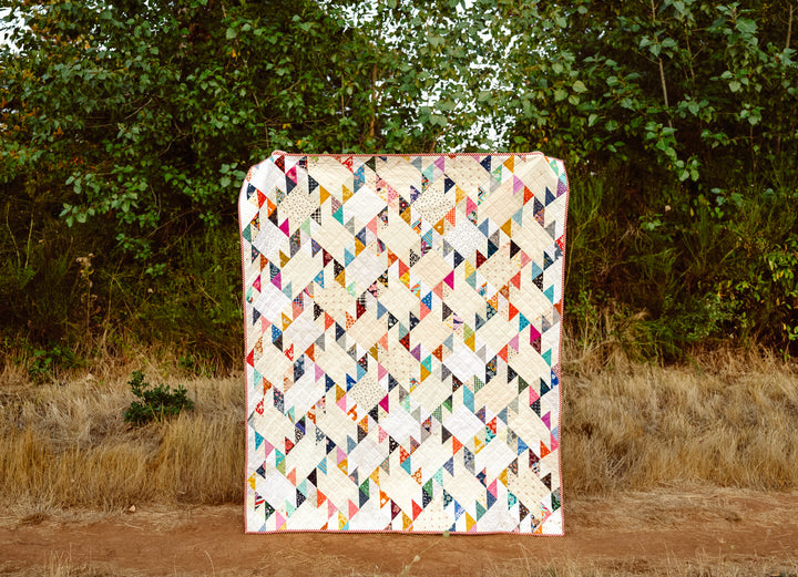 Scrappy Jenny Quilt Pattern made with a mix of colorful fabric scraps and low-volume background fabrics