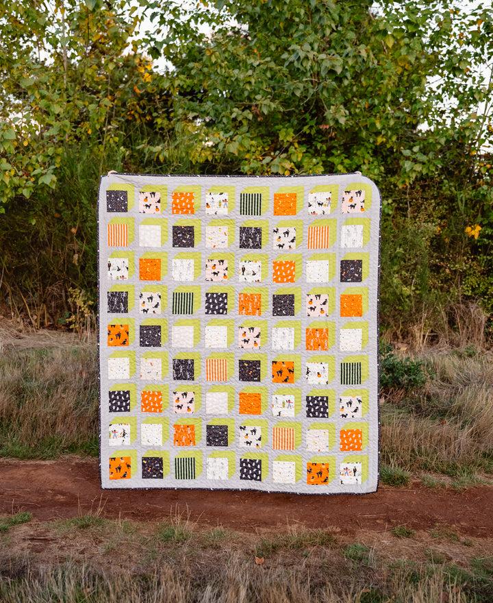 The Kristen Quilt made with Rifle Paper Co.’s Halloween fabric collection, featuring bright green accents, Ash background, and whimsical Halloween-themed prints.