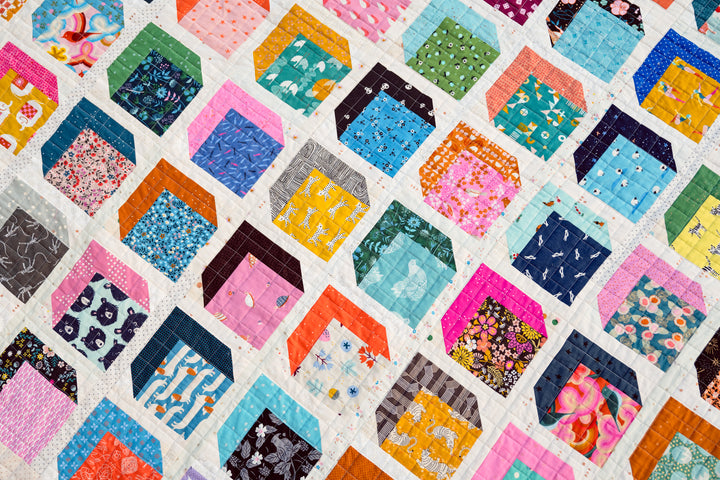 Scrappy Kristen Quilt made with vibrant Ruby Star Society and Cotton + Steel fabrics, featuring a colorful mix of charm squares and jelly roll strips on an organic grid quilting design.